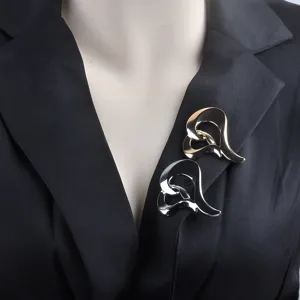 Detalle de broches de metal en forma de corazón dorado y plateado en un blazer de traje negro