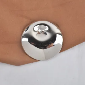 Macro detail of a polished stainless steel round brooch on brown fabric
