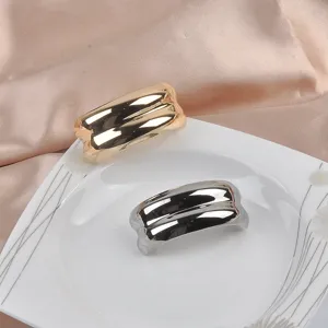 Close-up of gold and silver irregular C-shaped metallic brooches on a white plate