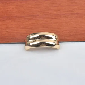 Detailed macro view of a golden C-shaped concave-convex metallic fashion brooch pin.