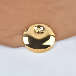 Close-up of minimalist gold-plated round brooch with a highly polished metallic finish