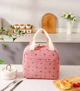 Pink floral corduroy insulated lunch bag placed on a kitchen counter with food props