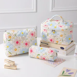 Set of three quilted cotton cosmetic bags with colorful floral patterns on a white background.