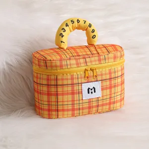Detail of yellow plaid cosmetic bag with numbered handle and soft fur background