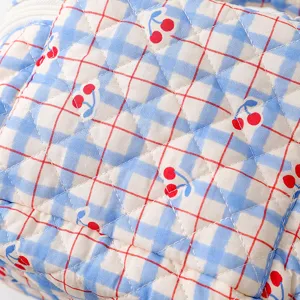 Detail macro view showing the quilted cotton fabric texture with blue plaid and cherry print