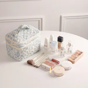 Detailansicht der geblümten gesteppten Kosmetiktasche mit Beauty-Accessoires auf einem Tisch.