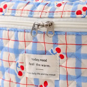 Detail view of quilted cotton cosmetic bag with cherry print and dual zippers