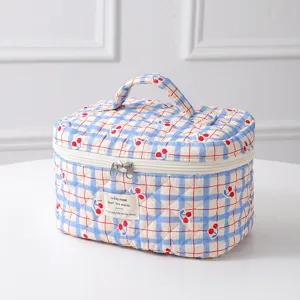 Macro detail of a quilted cotton cosmetic bag featuring a cute cherry gingham pattern