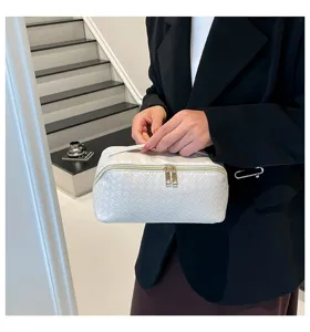 Close-up van een elegante witte gevlochten cosmetische tas vastgehouden door een persoon