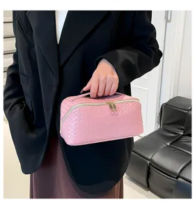 Detailopname van een roze geweven cosmetische tas vastgehouden door een elegant model