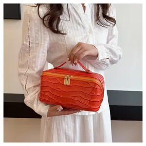 Elegant orange crocodile textured vanity case detail with gold zippers and handle
