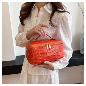 Model holding a stylish orange crocodile pattern large capacity cosmetic bag for travel