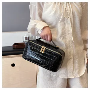 Close-up detail of a large capacity black crocodile pattern cosmetic bag with handle.