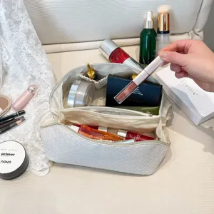 Gedetailleerd zicht op het ruime interieur van een witte geweven toilettas.