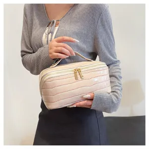 Elegant crocodile-embossed cosmetic bag held by an Asian model for travel size reference
