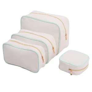 Set of four beige canvas storage pouches with mint green piping and gold-toned zippers