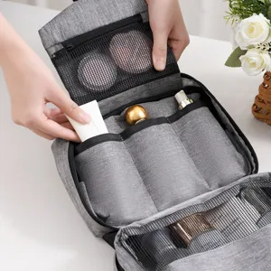 Detalle de cerca del neceser gris de viaje con múltiples compartimentos de malla