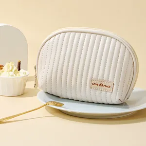 Cream PU quilted semi-circular makeup bag with zipper closure for travel storage