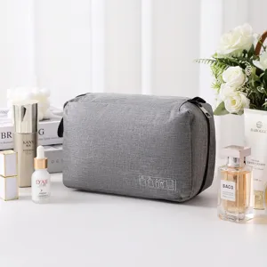 Neceser de viaje de tela gris con frascos de cuidado de la piel en una mesa blanca