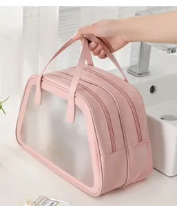 Pink travel toiletry bag with a handle being held in a bathroom setting showing its size
