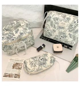 Detail view of quilted floral cotton cosmetic bags set with makeup accessories on a desk