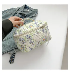 Detailed view of the handheld quilted cotton cosmetic bag with a cute floral pattern