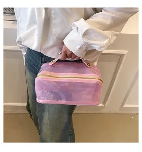 Detail of large pink transparent makeup bag held by hand, showing size and texture.