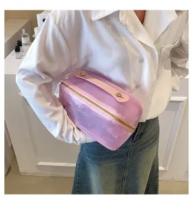 Close-up of stylish pink transparent travel cosmetic bag held by a fashion model