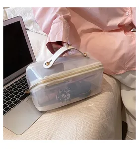 Lifestyle shot of a stylish transparent cosmetic bag used next to a laptop on a bed