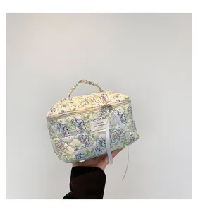 Close-up of a quilted cotton floral cosmetic bag with zip closure and white ribbon detail