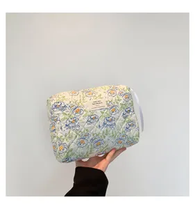 Detail view of a quilted cotton floral makeup bag with a soft blue flower pattern.