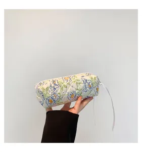 Detailed view of quilted cotton floral cosmetic bag with elegant ribbon zipper puller