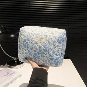 Large capacity quilted cotton makeup bag with blue floral print held in hand detail view