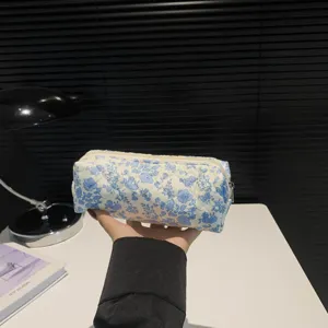 Detailed handheld view of a cute blue floral quilted cotton makeup bag for travel