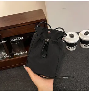 Mini bolso bandolera de lona negro minimalista en un acogedor ambiente de café.