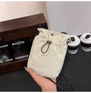 Primer plano de un bolso de tela minimalista para móvil con cordón de color crema