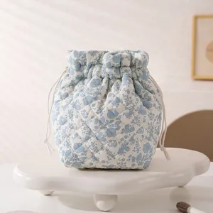 A close-up view of a floral quilted drawstring makeup bag on a white display stand