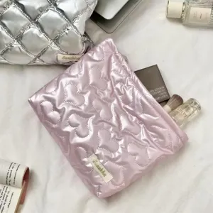 Detailed view of pink quilted heart cosmetic bag with glossy finish and storage