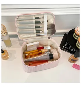 Detailed view of a spacious pink PU leather makeup bag filled with various cosmetics and brushes.
