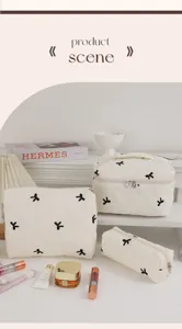 Ensemble de trois trousses de maquillage en coton matelassé blanc avec motifs de nœuds noirs