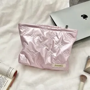 Detail of pink quilted PU cosmetic bag with bow patterns in lifestyle setting