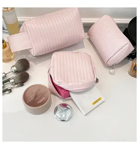 Detailed view of three pink quilted PU leather makeup bags with cosmetic props.