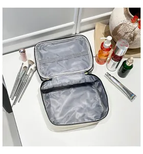 Vista dall'alto della borsa da trucco in PU aperta con interno grigio e porta pennelli