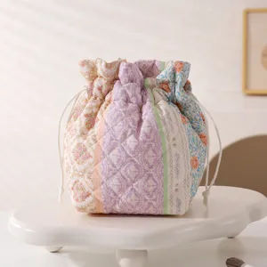 Detailed macro view of quilted floral drawstring makeup bag placed on white cloud pedestal