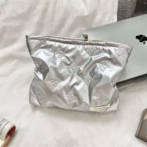 Close-up macro detail of silver quilted PU makeup bag with bow embroidery patterns