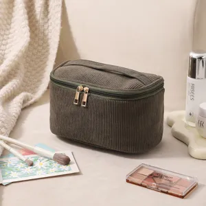Nahaufnahme einer olivgrünen Cord-Kosmetiktasche mit Kosmetika auf neutralem Hintergrund