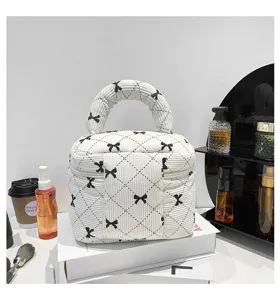Chic white corduroy cosmetic bag with black bow print on display with beauty props