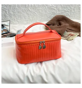 Detailed shot of a stylish orange quilted PU leather cosmetic bag with top handle.