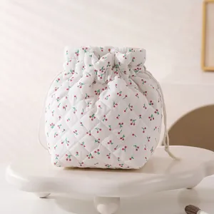 Detailed close-up view of a white quilted cherry print drawstring cosmetic storage bag