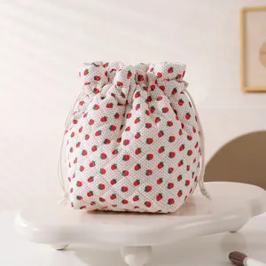 Detailed view of quilted strawberry print drawstring makeup bag with soft cotton texture
